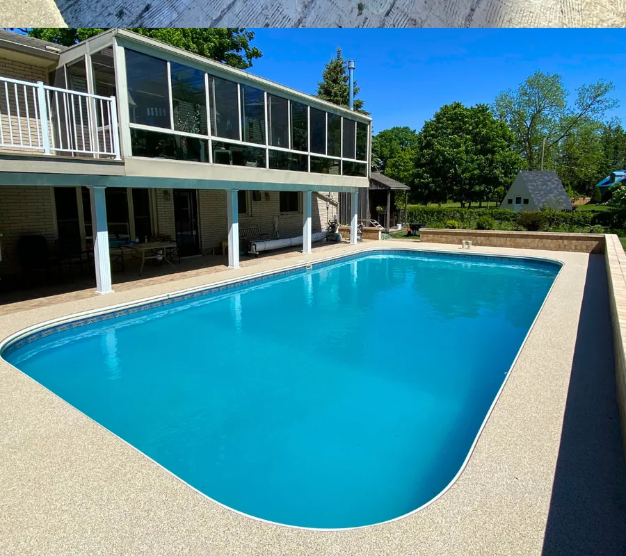 Pool deck after resurfacing with a light rubber surface around the same pool