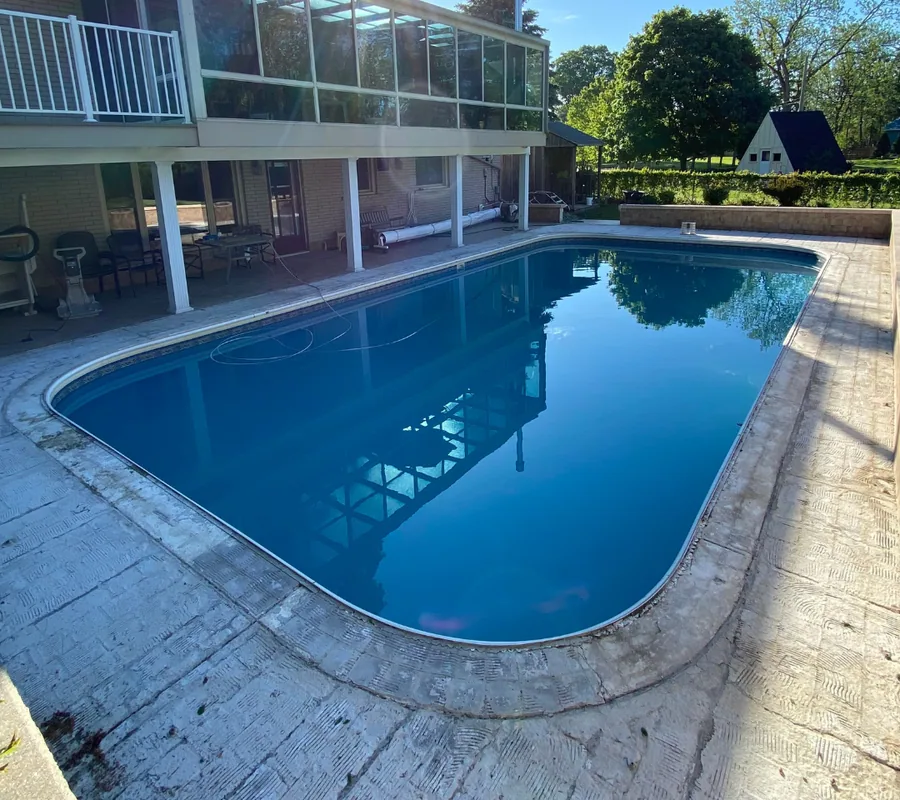 Pool deck before resurfacing: worn stamped concrete around a rectangular pool