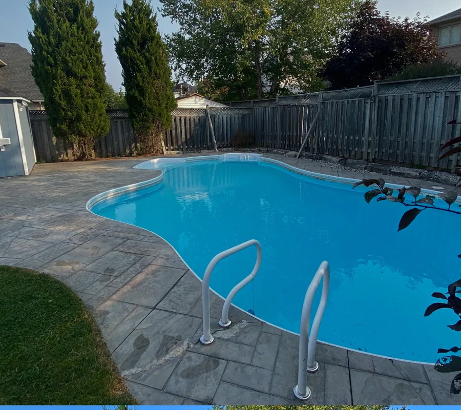 Pool deck before coating: weathered stamped concrete beside a kidney-shaped pool