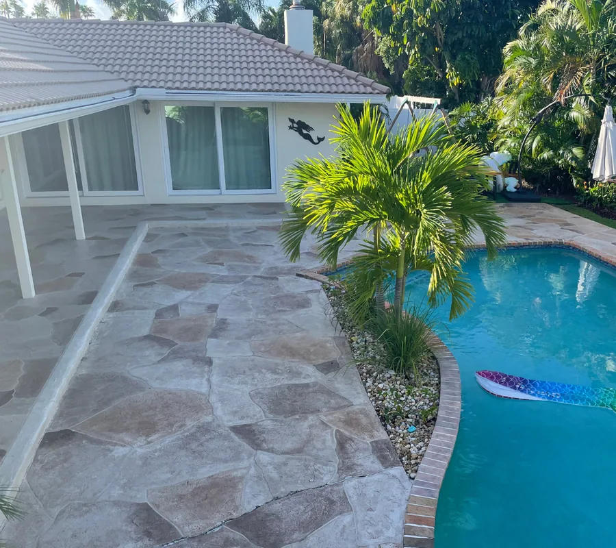 Pool patio before refinishing: cracked flagstone-pattern concrete beside a pool