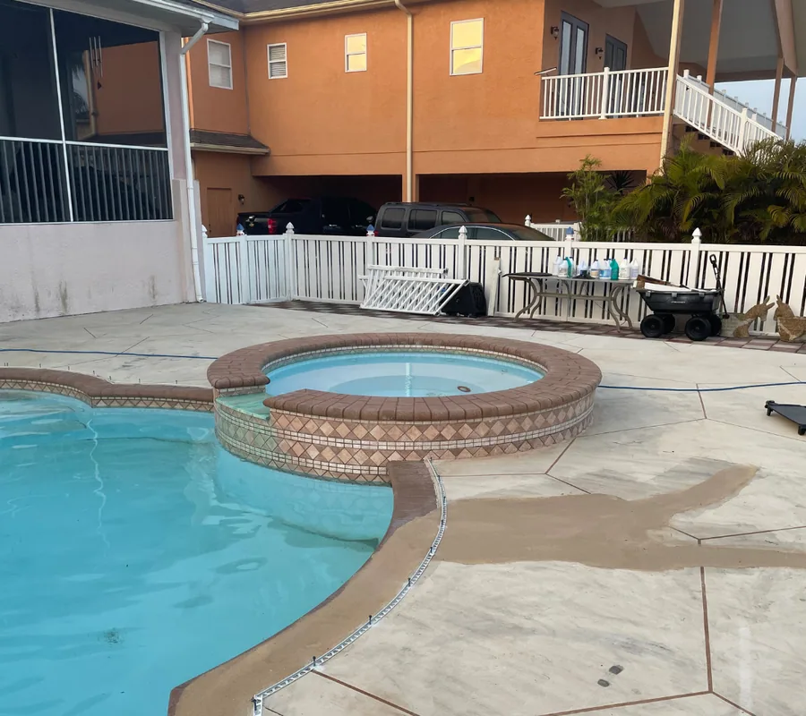 Pool deck before renovation: stained concrete around a spa and pool
