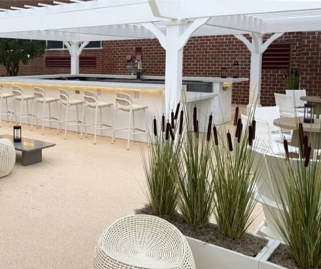 Natural marble stone surface installed on a commercial outdoor lounge, with a white pergola, bar seating and planters.